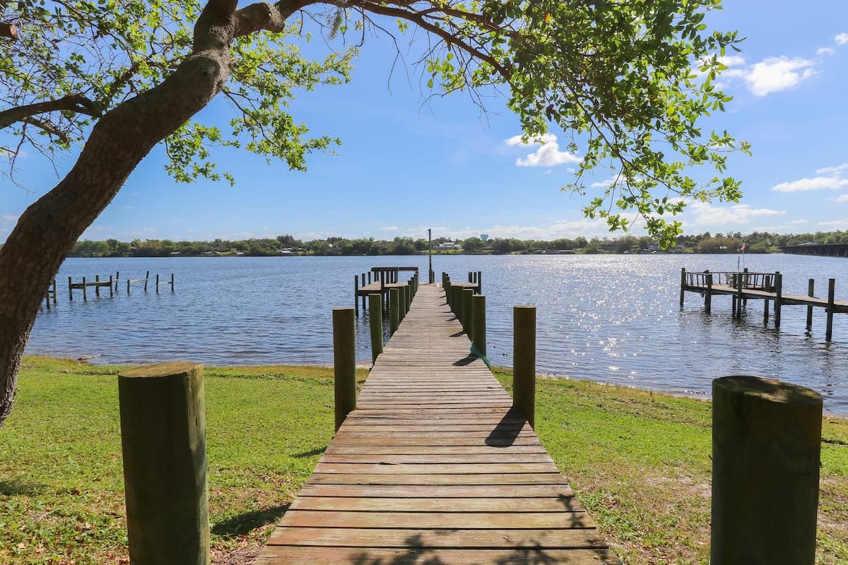A wooden dock running out into the Sebastian River, framed by a live oak